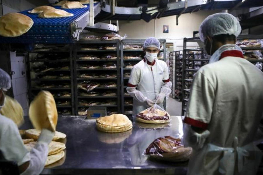Empleados, con equipo de protección personal, empacan pan en una panadería en la capital libanesa de Beirut. (PATRICK BAZ / AFP)