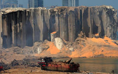 ‎Un silo de grano ahuecado y un barco carbonizado el día después de la explosión en el puerto de Beirut.‎ Foto: AFP.