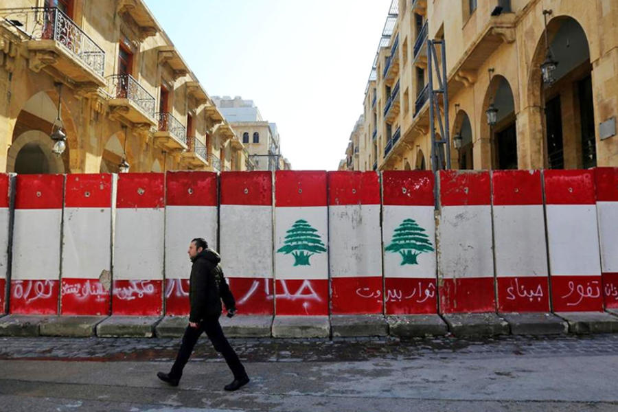 Un hombre pasa frente a barreras de concreto cerca del parlamento en Beirut. (Reuters)