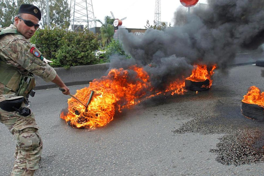 Un soldado libanés intenta abrir una carretera bloqueada por los neumáticos en llamas, en Zouk, al norte de Beirut (Foto REUTERS)