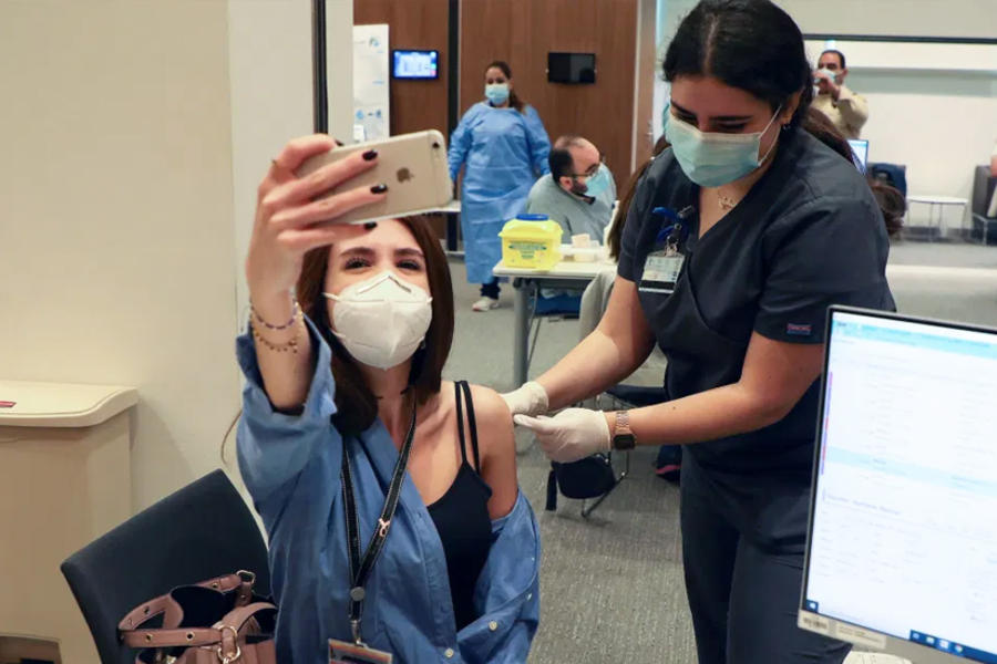 Una mujer toma una foto con su teléfono móvil mientras recibe la vacuna Pfizer-BioNTech contra COVID-19 en el centro médico de la Universidad Americana de Beirut el 14 de febrero de 2021. Foto: Reuters.