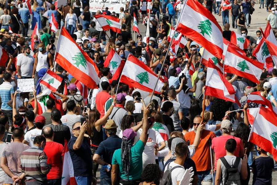 Los manifestantes ondean banderas nacionales libanesas mientras gritan consignas contra el Gobierno.