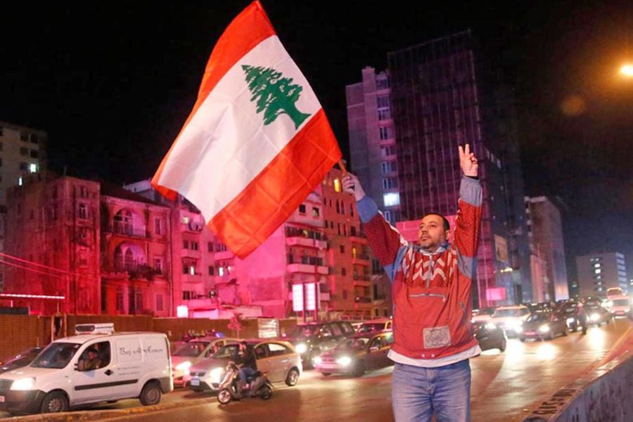 Un manifestante antigubernamental muestra el signo de la victoria y ondea una bandera libanesa, en Beirut, Líbano. AP.