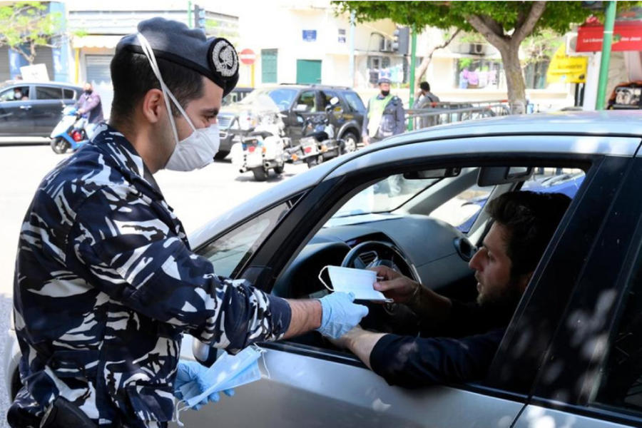 Un miembro de las Fuerzas de Seguridad Interna libanesa distribuye barbijos protectores en la calle Hamra, Beirut. AFP.