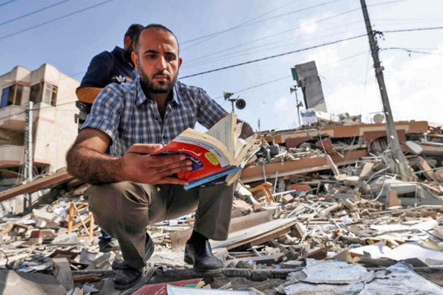 Un palestino sostiene un libro que sacó de debajo de los escombros del edificio Kuhail que albergaba la librería de Samir Mansour en la ciudad de Gaza. Foto: AFP.