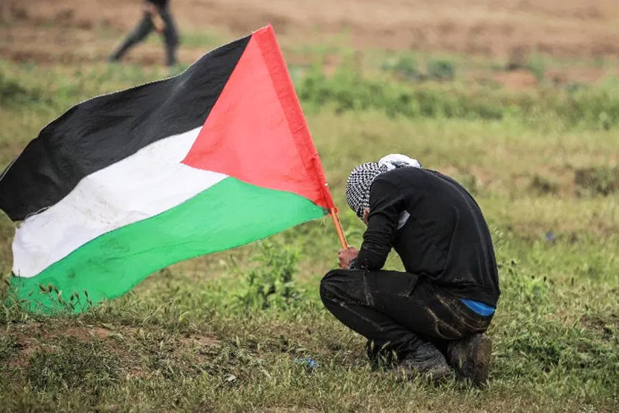 Un palestino sostiene una bandera durante una protesta dentro de las manifestaciones de la "Gran Marcha del Retorno" y el "Día de la Tierra Palestina" en el este del barrio de Shuja'iyya, Gaza, el 30 de marzo de 2019. Foto: Agencia Anadolu.