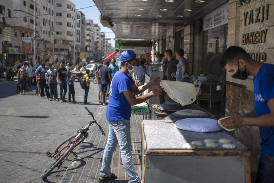 Palestinos hacen fila frente a una panadería para comprar pan durante el bloque impuesto tras el descubrimiento de nuevos casos de coronavirus en la Franja de Gaza. (AFP)