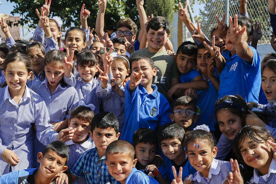 Niñas y niños que asisten a las escuelas de UNRWA en el campamento de refugiados de Jalazone Palestina en Cisjordania saludan durante un recreo | Foto: Marwan Baghdadi (© 2018 UNRWA)
