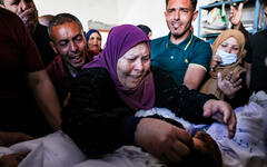La abuela y los familiares de tres niños de la familia Al-Tanani, asesinados en un ataque aéreo israelí, lloran sobre sus cuerpos antes de su entierro en Beit Lahya, en el norte de la Franja de Gaza, Palestina, 14 de mayo de 2021. Foto: AFP.