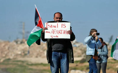 Palestino lleva un cartel que dice "Israel es un estado de apartheid", Cisjordania ocupada, 2019. Foto: AFP. Palestino lleva un cartel que dice "Israel es un estado de apartheid", Cisjordania ocupada, 2019. Foto: AFP.