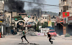 Jóvenes palestinos corren a refugiarse cerca de Jenin mientras el humo se eleva en medio de una ofensiva israelí en la ciudad ocupada de Cisjordania | Julio 3, 2023 (Foto: AFP)