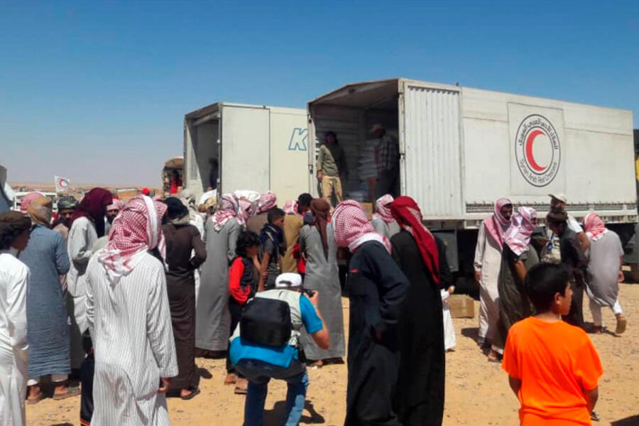 Los residentes de Rukban se reúnen frente a un camión de la Media Luna Roja Árabe Siria para recibir suministros de ayuda. Foto: MEE.