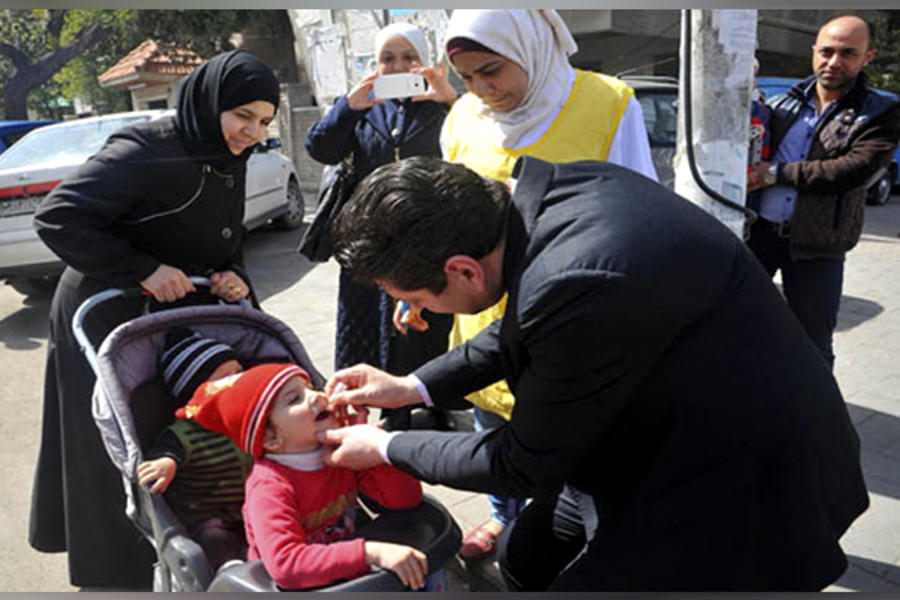 Ministro de Salud de la República Árabe Siria, Dr. Nizar Yazaji, suministrando vacuna a infante.
