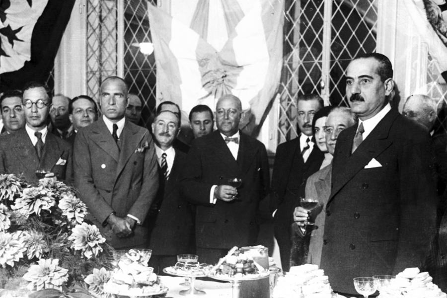 Sr. Moisés J. Azize y el Presidente de la Nación, Gral. Agustín P. Justo en el agasajo ofrecido con motivo de la inauguración del Colegio. En el fondo, las banderas de Siria, Argentina y Líbano (Marzo 15, 1933).