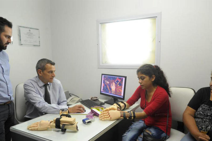 Con su mamá como testigo, Camila experimenta cómo usar las dos “manos nuevas”. El Dr. Claudio Brahim  y Lucas Abdala controlan en la computadora (Foto La Gaceta - Franco Vera).