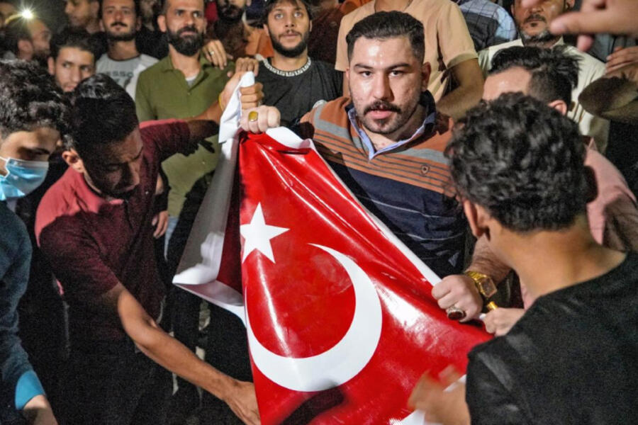 Iraquíes destruyen una bandera turca frente al centro de solicitud de visas de Turquía en una protesta en la ciudad central de Najaf, el 20 de julio de 2022. Foto: AFP.