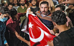 Iraquíes destruyen una bandera turca frente al centro de solicitud de visas de Turquía en una protesta en la ciudad central de Najaf, el 20 de julio de 2022. Foto: AFP.