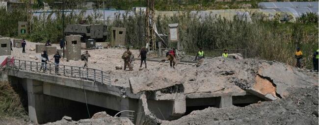 Soldados y civiles libaneses cruzan a pie el puente Qasmiyeh, tras su destrucción por el ejército israelí, este jueves en Líbano. Foto: AP.