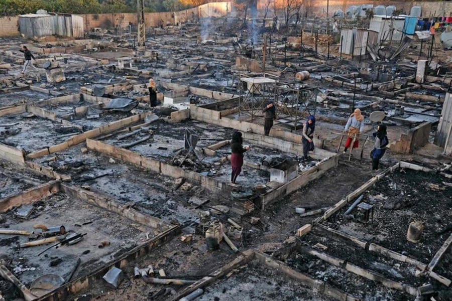 Los refugiados sirios toman sus pertenencias de los escombros en el campamento incendiado de Bhanine, en el norte de Líbano. AFP.