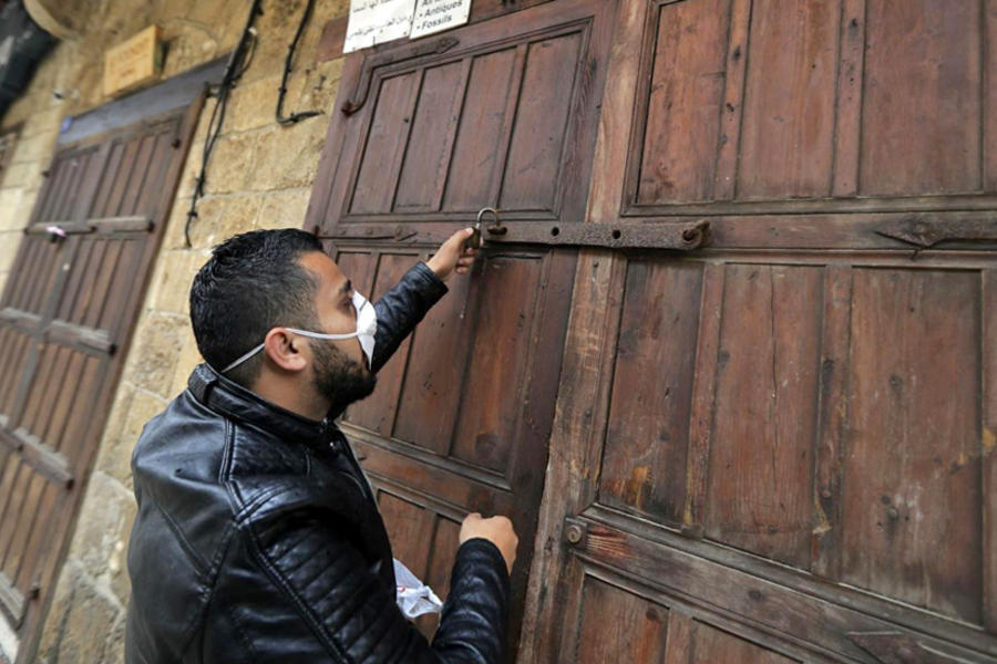 Un hombre cierra su tienda el 13 de marzo en la ciudad costera de Byblos, en el Líbano.