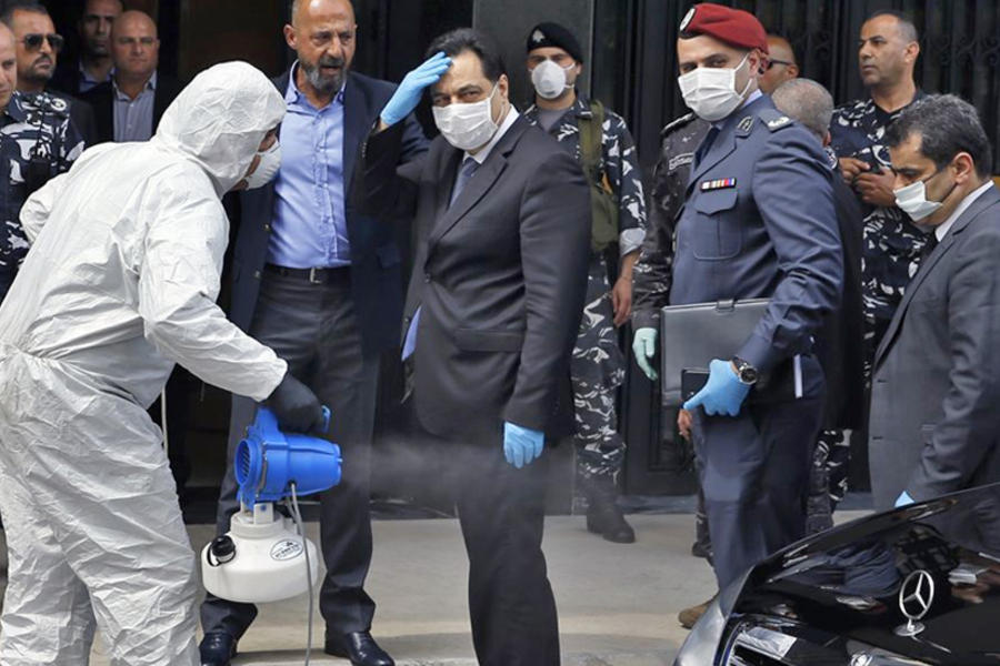 Un médico rocía desinfectante al primer ministro libanés Hassan Diab mientas arriba a una reunión del parlamento, en Beirut, Líbano, 21 de abril de 2020. (AP Photo/Bilal Hussein)