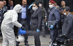 Un médico rocía desinfectante al primer ministro libanés Hassan Diab mientas arriba a una reunión del parlamento, en Beirut, Líbano, 21 de abril de 2020. (AP Photo/Bilal Hussein)