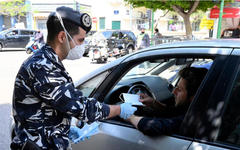 Un miembro de las Fuerzas de Seguridad Interna libanesa distribuye barbijos protectores en la calle Hamra, Beirut. AFP.