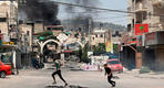 Jóvenes palestinos corren a refugiarse cerca de Jenin mientras el humo se eleva en medio de una ofensiva israelí en la ciudad ocupada de Cisjordania | Julio 3, 2023 (Foto: AFP)