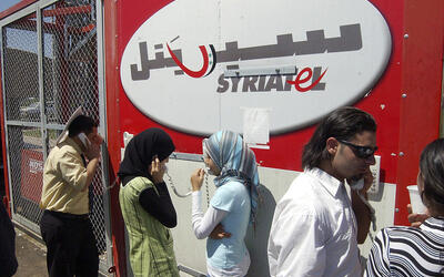 Refugiados libaneses en el cruce fronterizo sirio-libanés de Jdaidet Yabous hablan con sus familiares en el Líbano a través de teléfonos móviles proporcionados gratuitamente por la compañía de telecomunicaciones siria Syriatel, el 25 de julio de 2006 (Foto: AP)