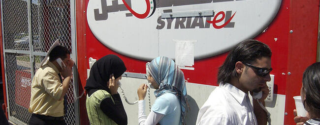 Refugiados libaneses en el cruce fronterizo sirio-libanés de Jdaidet Yabous hablan con sus familiares en el Líbano a través de teléfonos móviles proporcionados gratuitamente por la compañía de telecomunicaciones siria Syriatel, el 25 de julio de 2006 (Foto: AP)