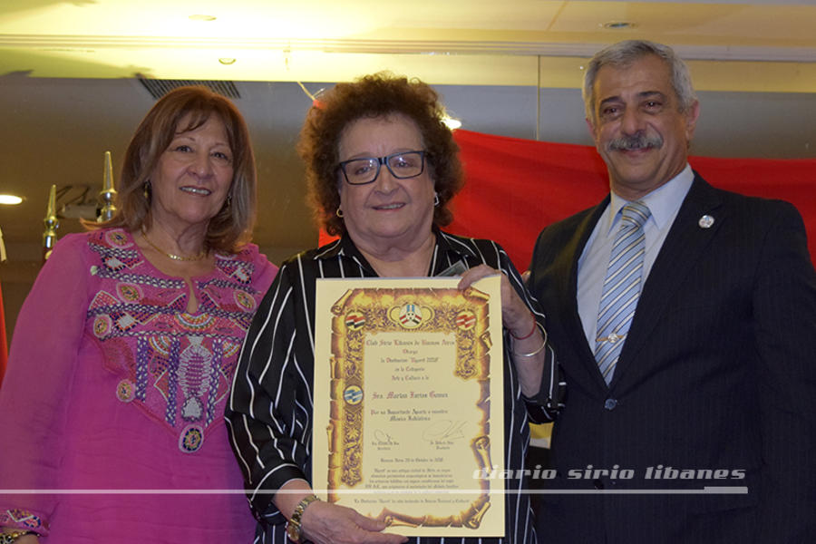 La Sra. Marian Farías Gómez recibe su distinción en Arte y Cultura, de parte de Claudio De Bas y Mirta Intilli
