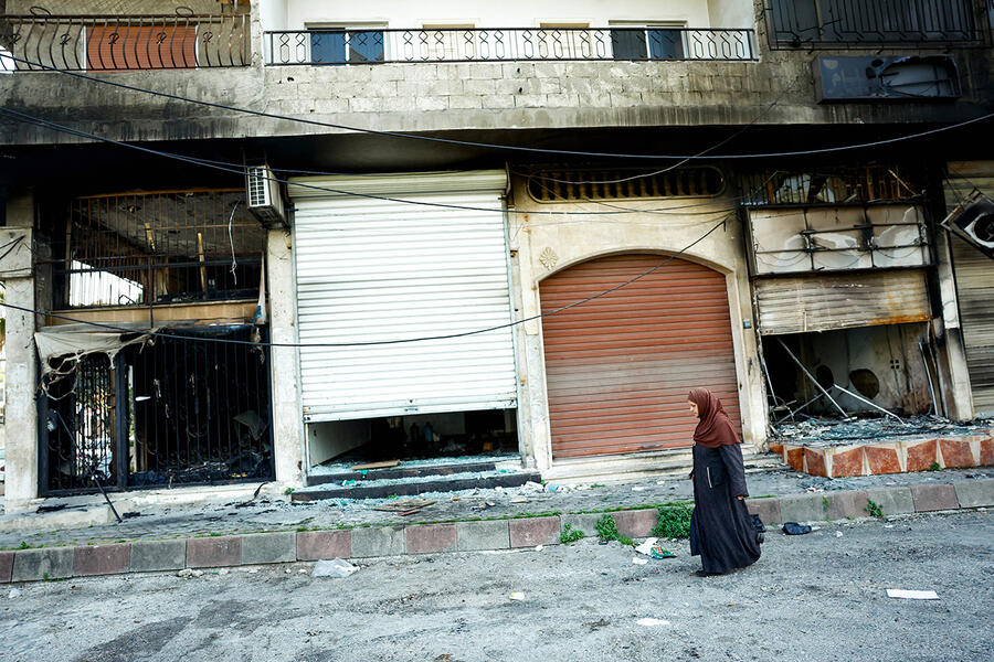 Una mujer pasa junto a un edificio incendiado en Baniyas, la ciudad más grande de la provincia de Tartus (Foto: Reuters/Stringer)