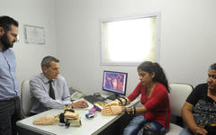 Con su mamá como testigo, Camila experimenta cómo usar las dos “manos nuevas”. El Dr. Claudio Brahim  y Lucas Abdala controlan en la computadora (Foto La Gaceta - Franco Vera).